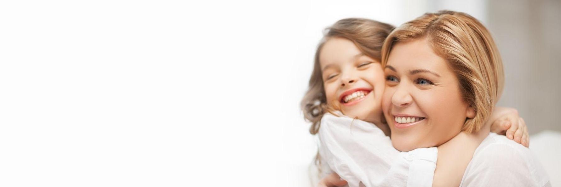 Mother & young daughter hugging & smiling l Kalaheo Dental Group