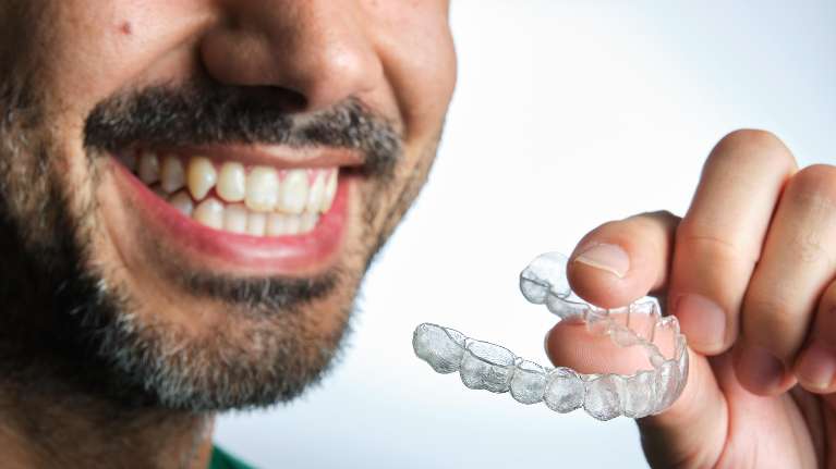 A man holding an Invisalign tray | dentist near Poipu