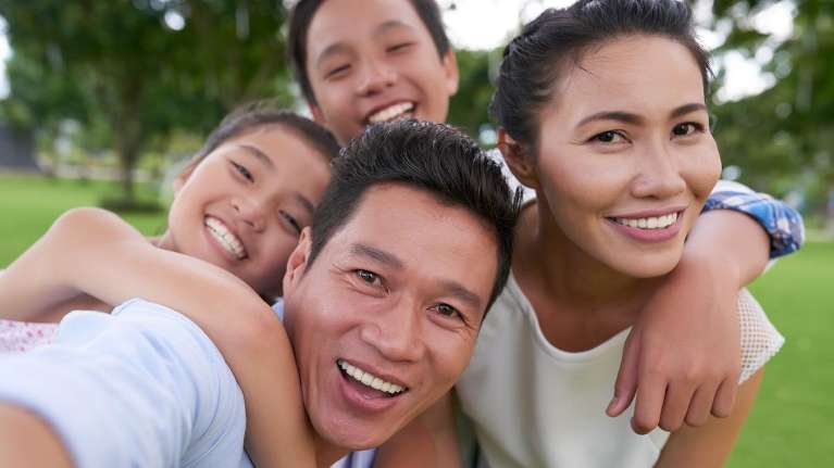 asian family of four smiling outside | family dentistry kalaheo